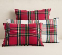 two red plaid pillows sitting on top of a bed