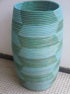 a large blue basket sitting on top of a tiled floor next to a wall and tile floor