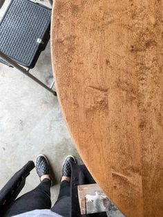 a person sitting at a wooden table with their feet up on the ground next to it