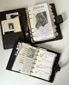 an open planner book sitting on top of a white table next to a black binder