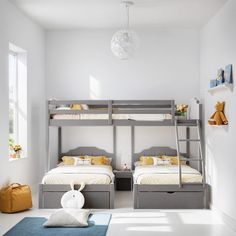 two bunk beds in a white room with yellow pillows and stuffed animals on the floor