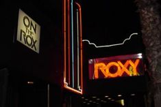 a neon sign on the side of a building that says roxxx in front of it