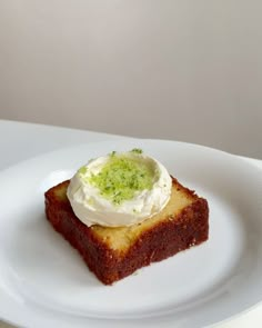 a piece of cake on a white plate with whipped cream and chives in the middle