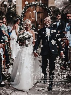 a bride and groom walk down the aisle as confetti is thrown around them