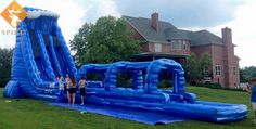 some people are standing in front of an inflatable water slide on the grass