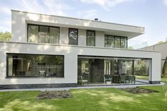 a modern house with large windows and grass