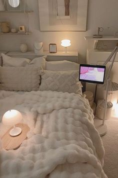 a bed with white blankets and pillows in a bedroom next to a lamp on the floor