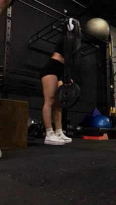 a woman lifting a barbell in a crossfit gym with balls on the floor