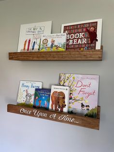 two wooden shelves with books on them and one shelf holding several children's books