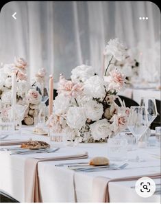 the table is set with white and pink flowers