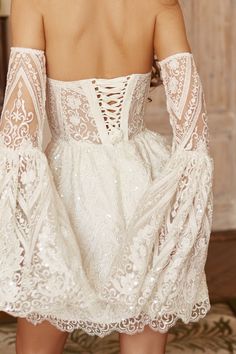 the back of a woman's white dress with long sleeves and openwork detailing