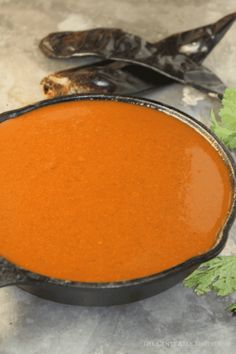 a pan filled with tomato soup and garnish on top of a white counter