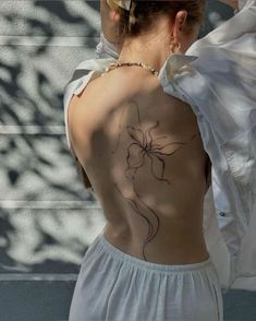 the back of a woman's body with tattoos on her upper and lower back