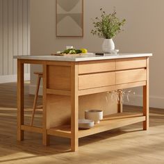 a kitchen island with two wine glasses on it and a potted plant in the center