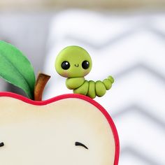 an apple with a little green bug sitting on it's side next to a leaf