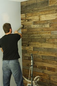 a man is painting a wooden wall with wood planks