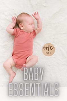 a baby laying on top of a white blanket next to a wooden sign that says one month