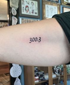 a person with a small tattoo on their arm that says 3003 in black ink