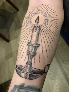 a tattoo with a lit candle on it's arm and an ink pen in the middle