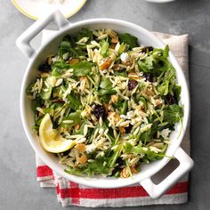 a white bowl filled with salad on top of a red and white striped napkin next to a plate