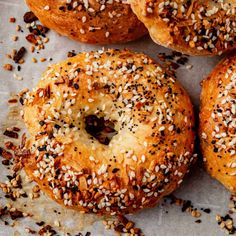 bagels with sesame seeds and poppy seeds on top sitting on a piece of parchment paper