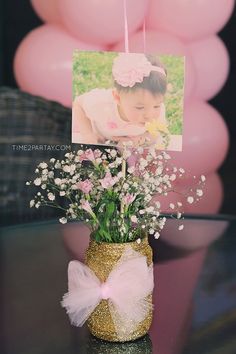 a vase filled with baby's breath flowers on top of a table next to balloons