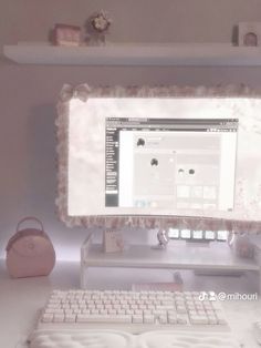 a computer monitor sitting on top of a desk next to a pink purse and keyboard