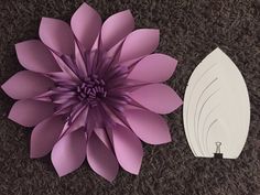 a paper flower next to a white piece of paper on the ground with scissors in it