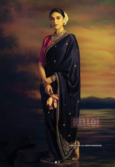 a woman in a sari standing on a rock