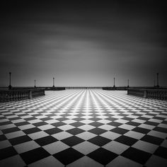 a black and white photo of a checkerboard floor in the middle of an empty room