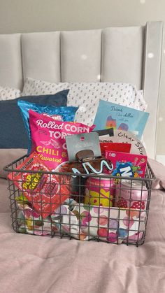 a basket filled with books on top of a bed next to pillows and pillow cases