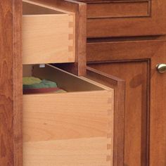 an open drawer in the middle of a kitchen cabinet with granite counter tops and wooden cabinets