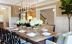 a dining room table with white flowers in vases on it and candles hanging from the ceiling