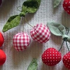 red and white fabric with green leaves and apples hanging from it's sides on a table