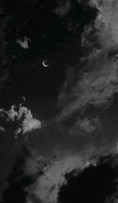 black and white photograph of the moon in the sky with clouds around it at night