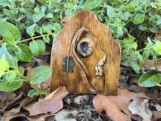 a small wooden house with a blue stone in it's center surrounded by leaves