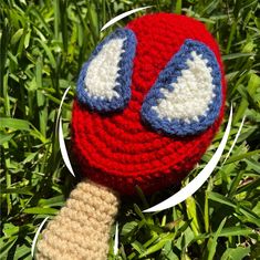 a crocheted red, white and blue ball with eyes on it laying in the grass