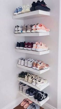 three white shelves filled with different types of shoes on top of each other in front of a wall