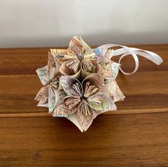 an origami flower made out of money sitting on top of a wooden table