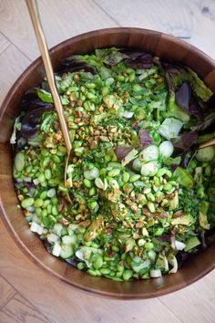 a wooden bowl filled with green vegetables and chopsticks