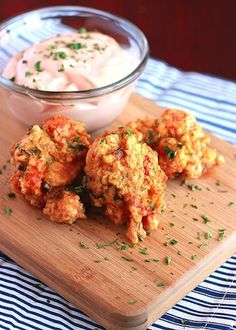 some food is sitting on a cutting board next to a bowl of ranch dips