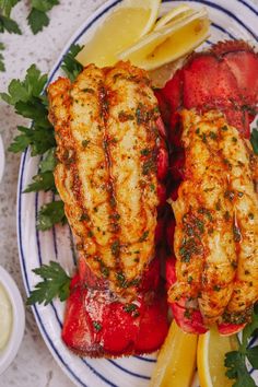 two fish fillets on a plate with lemons and parsley