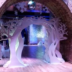 an archway decorated with paper cut trees and snowflakes on the floor in front of a brick wall