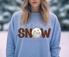 a woman wearing a blue sweatshirt with the words let it snow on it