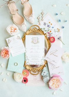 the wedding stationery is laid out on top of the bride's dress and shoes