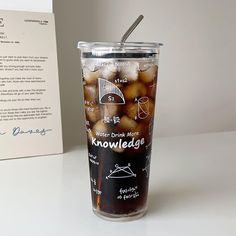 a glass with some kind of food in it next to a card and paper on the table