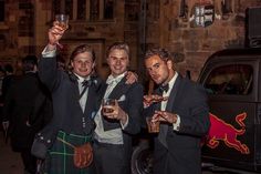 three men in kilts holding up drinks