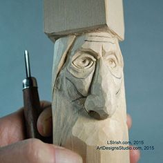 a wooden carving of a man's head with a pen in his hand