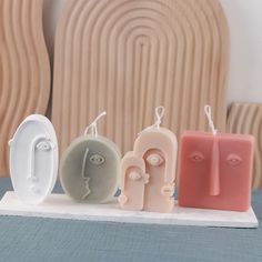 four soaps with different shapes and colors on a white tablecloth in front of a wooden headboard