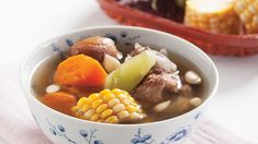 a bowl of soup with corn, carrots and meat